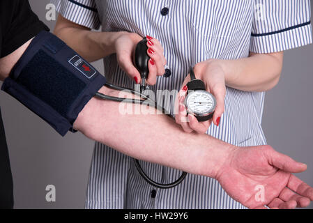 L'infermiera usando un monitor della pressione del sangue di un paziente Foto Stock