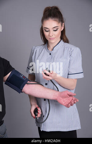 L'infermiera usando un monitor della pressione del sangue di un paziente Foto Stock