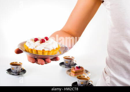 Donna di mano azienda piccola torta sul bel set piastra Foto Stock