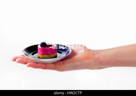 Womans mano azienda piccolo dessert torta sul delicato piastra set Foto Stock
