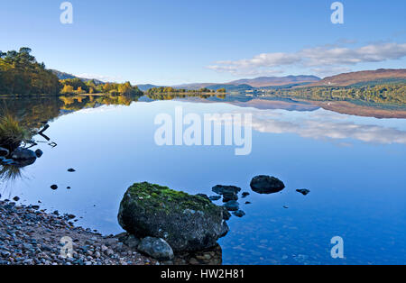 Vista sull'estremità occidentale del Loch Rannoch, Highland Perthshire, colline e boschi si riflette nell'acqua calma su una bella giornata d'autunno Foto Stock