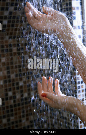 Le mani della donna nella doccia sotto l'acqua corrente Foto Stock