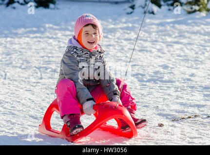 Il Toddler ragazza in tuta invernale in slittino divertirsi con la neve Foto Stock