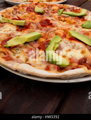 Pizza sul legno scuro del tavolo con ingredienti freschi Foto Stock