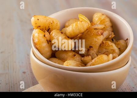 Foto orizzontale con due ciotole impilati piena di gnocchi fatti in casa. Porzione di pasta viene collocato su vintage tagliere in legno con superficie usurata. Foto Stock