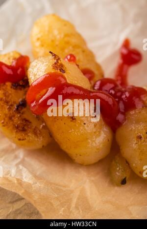 Foto verticale con diversi pezzo di gnocchi fatti in casa sul pezzo di carta. Porzione di pasta viene collocato su vintage tagliere in legno con superficie usurata. Red ket Foto Stock