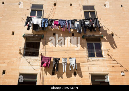 Il lavaggio e la biancheria stesa ad asciugare su linee di lavaggio su un vecchio edificio in Valletta, Malta Foto Stock