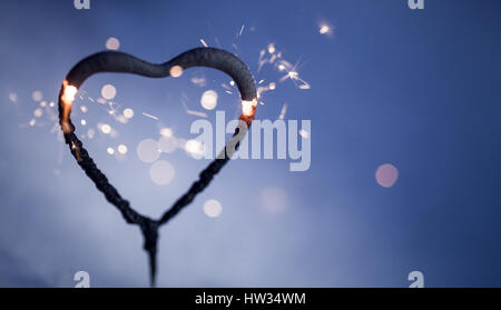 Forma di cuore sparkler bruciare e incandescente al buio Foto Stock