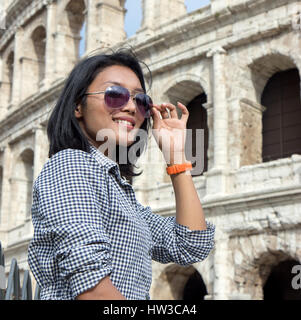 Turisti asiatici in un tour del centro storico di Roma. Donna che mantiene gli occhiali da sole vicino al Colosseo, Roma, Italia. Foto Stock