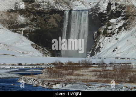 L'Islanda, Skogar, Skogafoss, Skogafoss cascata circondata da neve e ghiaccio in inverno Foto Stock