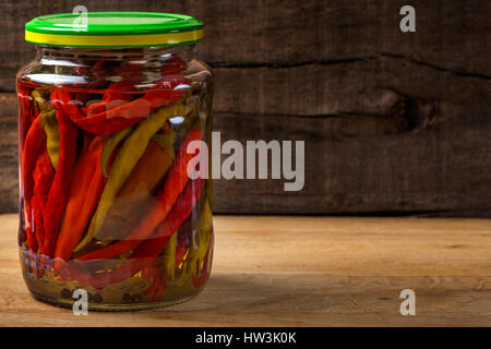 Marinata di peperoncino in vaso su sfondo di legno Foto Stock