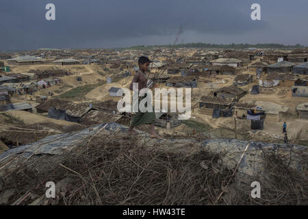 6 marzo 2017 - Cox's Bazar, Chittagong, Bangladesh - un ragazzo di profughi tentando di proteggere la sua casa di fortuna dalla pioggia in Kutupalong recentemente allargato camp il 6 marzo 2017 In Cox bazar, Bangladesh. Circa 70.000 Rohingya musulmani sono fuggiti in Bangladesh dal Myanmar a partire da ottobre 9, 2016 dopo l'esercito birmano ha avviato le operazioni di sdoganamento in risposta a un attacco alla polizia di frontiera. Ci sono più di 30.000 rifugiati registrati in Bangladesh ma le autorità stima che 300.000 a 500.000 Rohingya non registrati sono anche già vivono qui. Come risultato, la maggior parte di questi rifugiati non registrati ar Foto Stock