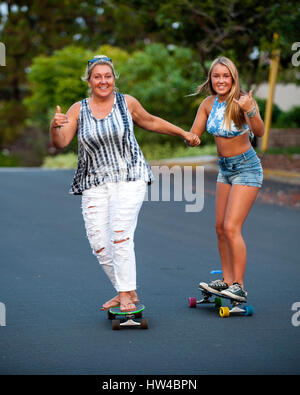 Caucasian madre e figlia per mano mentre lo skateboard Foto Stock