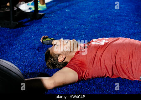 Affaticato uomo caucasico posa su campo sportivo Foto Stock