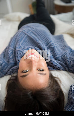 Sorridente razza mista donna posa sul letto Foto Stock