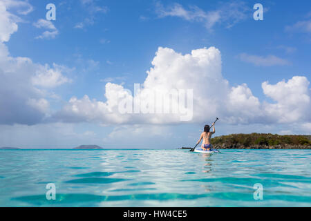 La donna caucasica paddling surfboard sull oceano tropicale Foto Stock