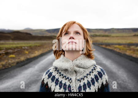 Caucasian donna che indossa un maglione in strada cercando Foto Stock