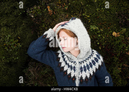 Caucasian donna che indossa un maglione posa su moss Foto Stock