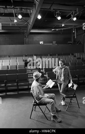 Attori caucasici ripassando con script in teatro Foto Stock