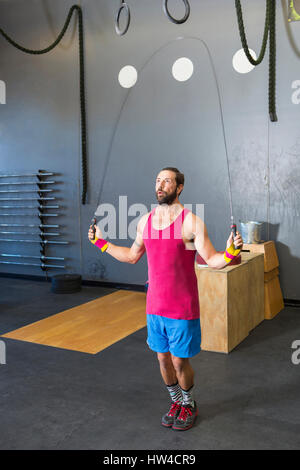 Razza mista uomo salto con la corda in palestra Foto Stock