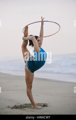 Ginnasta caucasica praticando con gomma sulla spiaggia Foto Stock