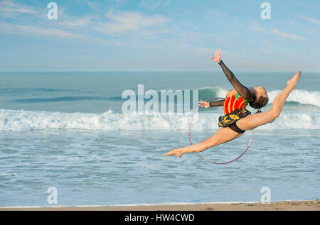 Ginnasta caucasica jumping con gomma sulla spiaggia Foto Stock