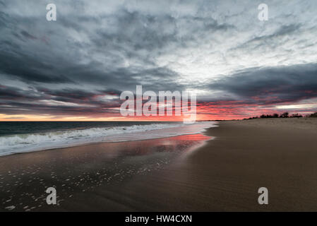 Le onde del mare sulla spiaggia al tramonto Foto Stock