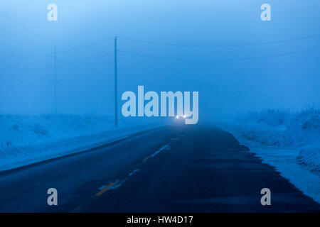 Fari di avvicinamento dall'auto in inverno Foto Stock