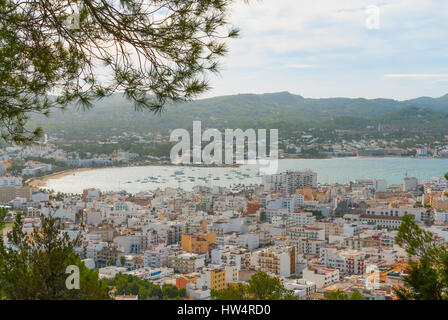 Visualizzare naturalmente attraverso gli alberi di framing, dalla collina della vicina città: San Antonio Sant Antoni de Portmany a Ibiza. Marina con barche ormeggiate. Foto Stock