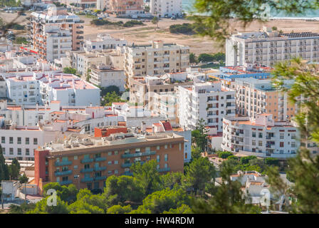 Visualizzare naturalmente attraverso gli alberi di framing, dalla collina della vicina città: San Antonio Sant Antoni de Portmany nelle Isole Baleari, Ibiza, Spagna. Foto Stock