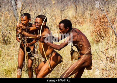 I Boscimani persone che simula una battuta di caccia con arco e frecce a Grashoek, Namibia settentrionale Foto Stock