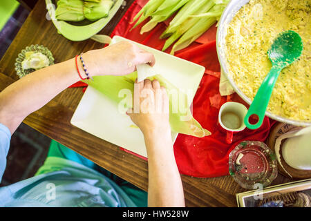 Una donna che prepara un piatto Mesoamerican chiamato "Tamales". Si tratta di un piatto fatto di masa che è avvolto in Corn buccia e deve essere cotto a vapore. Foto Stock