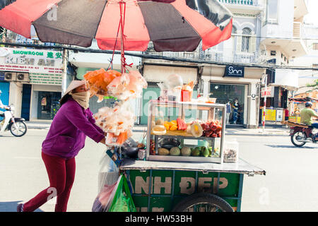 La città di Ho Chi Minh, Vietnam - Marzo 29, 2014: donna vietnamita nel cappello conico vende frutta sulla strada di Saigon, Vietnam. Foto Stock