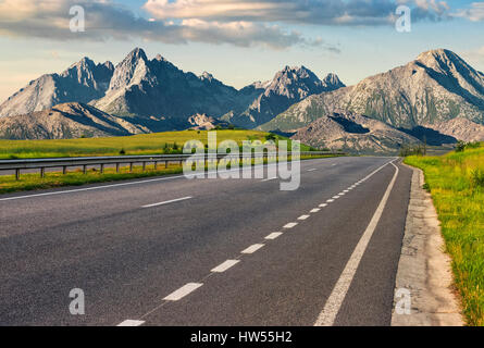 Destinazione di viaggio Concetto di immagine. Paesaggio composito dei Monti Tatra montagna cresta. Asfalto semplice autostrada attraverso colline verdi conduce ad alte cime. Foto Stock