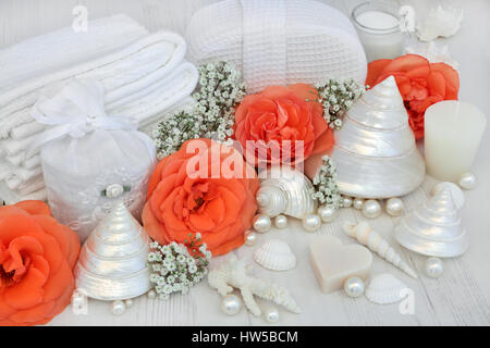 Skincare bellezza prodotti detergenti con orange rose fiori, conchiglie e perle su distressed bianco sullo sfondo di legno. Foto Stock