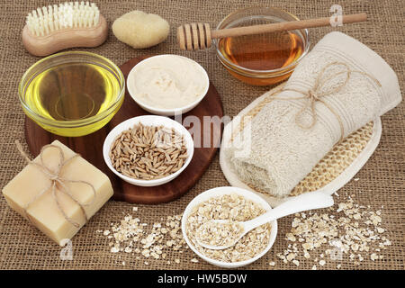 Pelle e prodotti per la cura del corpo per purificare e calmare i disturbi della pelle con avena, miele, olio, crema idratante naturale e sapone su sfondo di Hesse. Foto Stock