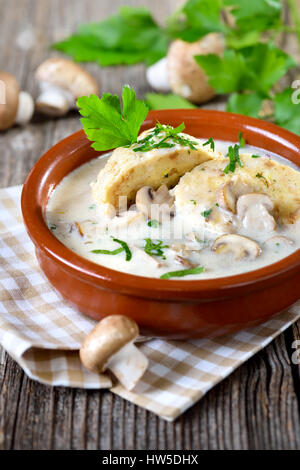 Salsa di funghi con gnocchi di pane è servita in una coppa in ceramica su una tavola di legno Foto Stock