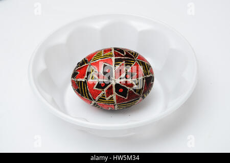 Un uovo di pasqua è decorata con tradizionali folk ucraino ornamento utilizzando una cera-metodo di resist. Il pysanka è coperto con cera e tinto di rosso e di giallo Foto Stock