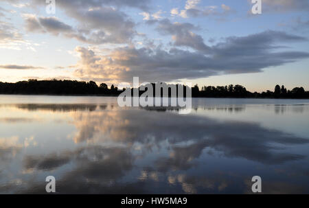 Prima dell'alba sul lago in campagna polacca - cielo nuvoloso e silhouette di foresta Foto Stock
