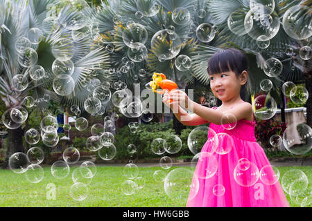 Asian poco ragazze cinesi bolle riprese dal ventilatore di bolla nel Parco Foto Stock