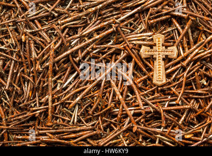 Golden cross su alcuni utilizzati arrugginita vecchi chiodi. Foto Stock