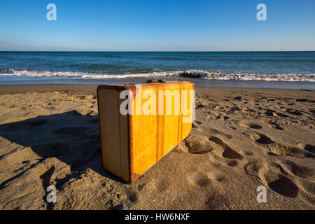 Vecchia valigia in pelle si erge eretta in corrispondenza di una spiaggia sabbiosa. Fuengirola provincia di Malaga. Costa del Sol, Andalusia Spagna Meridionale.Europe Foto Stock