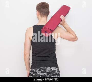 Giovane Azienda materassino yoga vista dal retro Foto Stock
