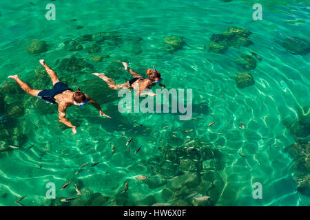 Giovani amici divertendosi lo snorkeling in un ambiente tropicale mare di corallo con pesce Foto Stock