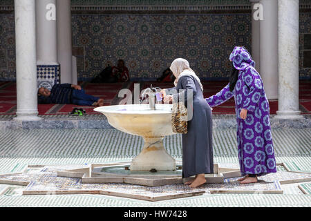Fes, Marocco. Le donne di ottenere l'acqua per le abluzioni, Mausoleo di Moulay Idris II, Fes El-Bali. Foto Stock