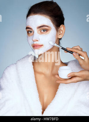 Giovane donna con idratante maschera per il viso e le mani del parrucchiere. Foto di Pretty Woman riceve i trattamenti della spa. Beauty & Skin care concept Foto Stock