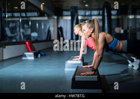 Due giovani donne atletica facendo spingere ups vista laterale Foto Stock