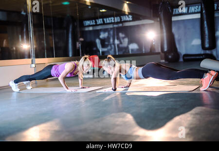 Due belle giovani donne atletica facendo spingere ups insieme. Foto Stock