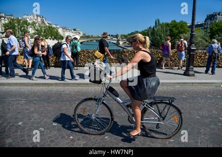 Francia, Parigi, zona elencata come patrimonio mondiale dall' UNESCO, Bridgeof Archeveche, giovane donna su una bicicletta che passa su un ponte con i pedoni in background (archivio) Foto Stock