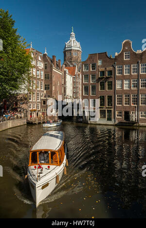 AMSTERDAM, Paesi Bassi - 27 settembre 2016: Barche crociera sul canale con la Chiesa di San Nicola torre in distanza. Foto Stock